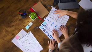 Mulheres olhando papeis de estatistica em cima de uma mesa de madeira