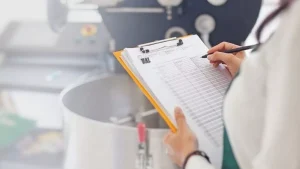 pessoa em frente a uma panela escrevendo em uma planilha em cima de uma prancheta